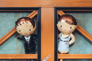 Wedding celebration decorations showcase charming balloon figures of a couple dressed elegantly, nestled in wooden surroundings