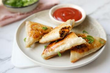 Traditional Indian appetizer featuring vegetable-stuffed samosas served with hot dipping sauce.