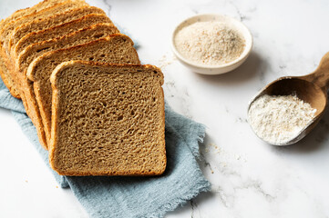 Fiber-rich whole grain bread slices with a bowl of flour, symbolizing healthy eating.