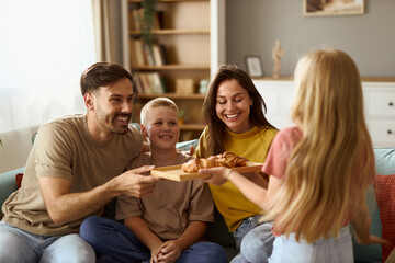 Happy  family enjoying in their time at home while daughter is bringing croissants to her parents...