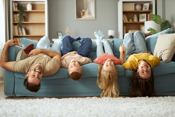 Happy  family having fun while lying upside down on sofa in the living room.