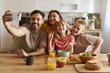 Happy  family having fun while taking a selfie during breakfast in dining room.