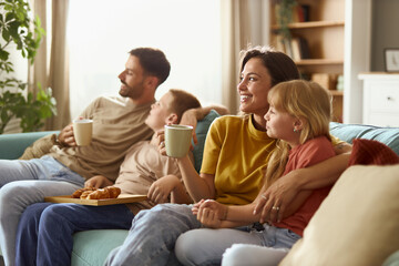 Happy parents and their kids day dreaming while relaxing on sofa at home.