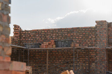 Construction workers are busy stacking bricks on site to build a sturdy wall while sunlight...