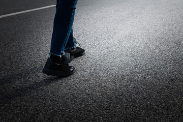 Woman feet walking on asphalt road