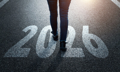 Woman standing on asphalt road with the text 2026. Concept of new year, fresh beginning