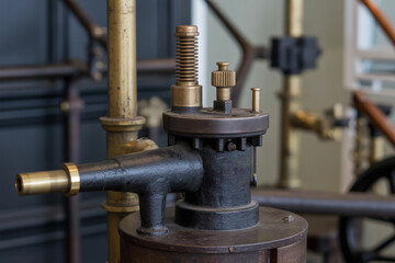 A close up of a vintage machine with brass and black metal components in a workshop setting indoors