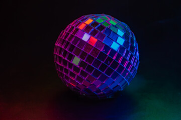Image of a disco ball against a dark background, reflecting colored dots due to surrounding light sources Connotes fun and festive atmosphere associated with parties