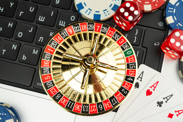 Image showcases a vintage roulette wheel surrounded by playing cards, chips, and a keyboard with...