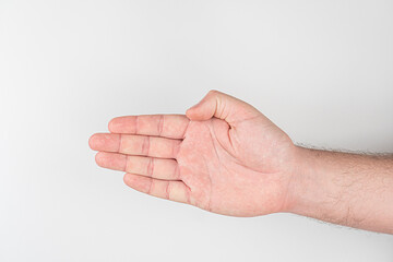A fair-skinned human hand is shown, palm upwards, hovering above a light gray surface in an indoor...