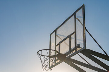 A metal basketball hoop with a square backboard and white net, standing on a gray basketball court...