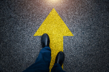 Man standing on asphalt road with the arrow sign