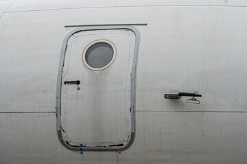 A weathered, open-door passenger jet with a round window and secondary viewing point, possibly...