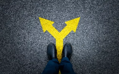 Gordijnen Man standing on asphalt road with arrow signs © xy