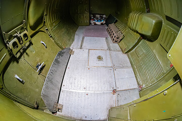 Cockpit interior view, primarily green control panels and dials, artificial lighting