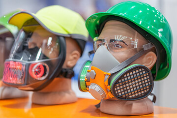 Two life-sized mannequins, back to back Each wearing a different respirator mask and safety helmet...