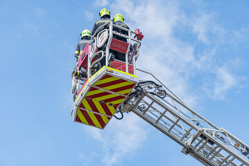 Fototapeta premium Rescue operation in progress, overcast day, fire truck with extended ladder, rescue team members, helmets, protective gear, purposeful body language, diffused light, red fire truck