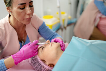 Beautician injecting filler into woman's nose for rhinoplasty