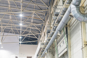 Empty industrial space with white tiled floor, high ceiling, exposed metal beams, fluorescent...