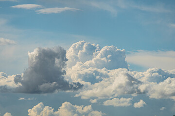 Distant view of large, billowing cumulus clouds under a dramatic sky, dominated by whites, grays, and subtle blues The lighting suggests it is either dawndusk or an overcast day with sunlight break