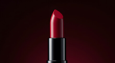 Crimson lipstick with a sleek black case stands out against a deep red background, showcasing luxury and cosmetic elegance.
