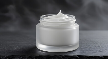 Elegant frosted glass jar presents luxurious moisturizing cream on textured slate backdrop, conveying beauty and skincare.
