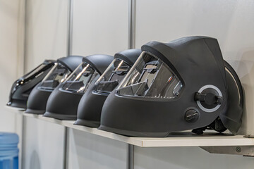 Neatly arranged black sports helmets on white shelves, clear visors, sleek designs, possibly racing...