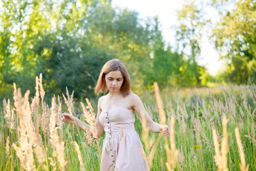A beautiful woman stands in the forest on a summer day. A white dress and transparent panties are...