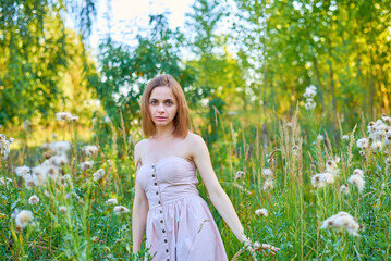 A beautiful woman stands in the forest on a summer day. A white dress and transparent panties are...