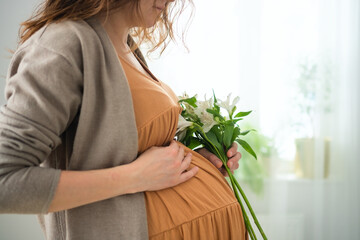 Detailed shot of pregnant woman's hands softly stroking her rounded abdomen. Intimate moment of prenatal bonding and quiet happiness.