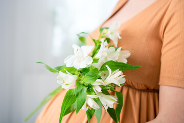 Serene close-up of pregnant woman's hands with white blooms gently resting on rounded abdomen. Heartwarming prenatal bonding scene.