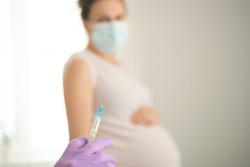 Healthcare worker administering vaccine to expecting mother. Focused shot on medical procedure protecting both maternal and newborn health through immunization.