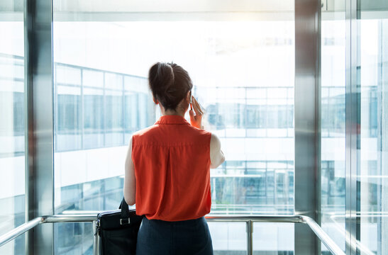 Businesswoman using mobile phone in the elevator