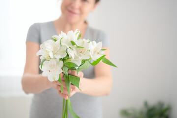 Expecting mother cradling white flowers while lovingly touching her baby bump. Pregnant woman