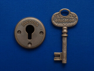 Keyhole with the inscription 'Success' and a bronze key with the engraving 'Education' on a blue background. Education and study concept. Top view for poster, card, design
