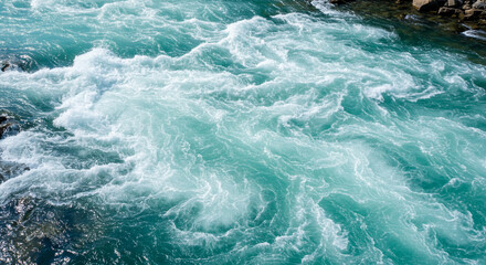 Rapid turquoise river currents creating turbulent white water ripples flowing downstream dynamic