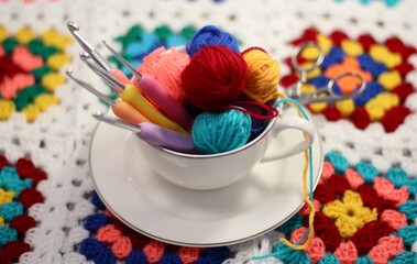 A cup and a saucer with clews balls of yarn wool and crocheted blanket handmade craft bright photo	
