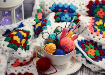 A cup and a saucer with clews balls of yarn wool and crocheted blanket handmade craft bright photo	
