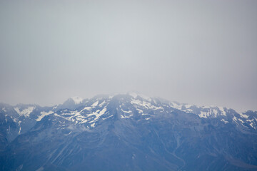 Misty Snow-Capped Mountains Under Cloudy Sky