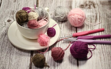 A cup and a saucer with clews balls of yarn wool and crocheted blanket handmade craft bright photo	
