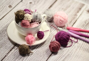 A cup and a saucer with clews balls of yarn wool and crocheted blanket handmade craft bright photo	
