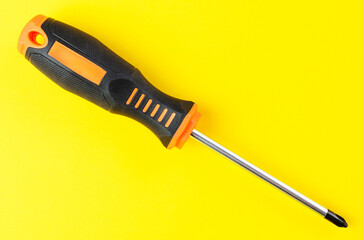 Cross-head screwdriver on bright yellow background isolated closeup sharp image