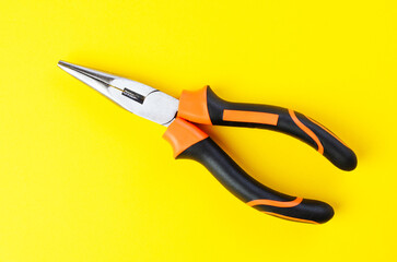 Close-up of metal pliers on vibrant yellow background with sharp details