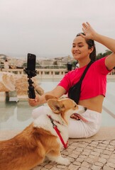 Young girl with Corgi recording video on phone share via app her travel vacation. Gen Z influencer...