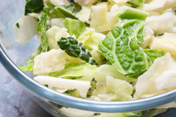 Frozen sliced cabbage defrosting in a glass bowl background backdrop. On a green marble background.