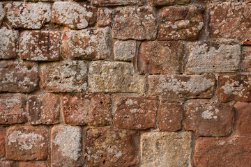 Old medieval weathered sandstone textured wall background backdrop with lichen growing on the surface.
