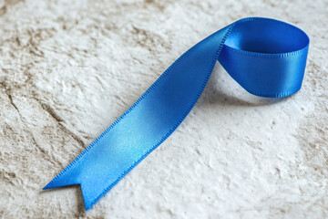 Blue ribbon isolated on a soft, white background, symbolizing child abuse awareness. 