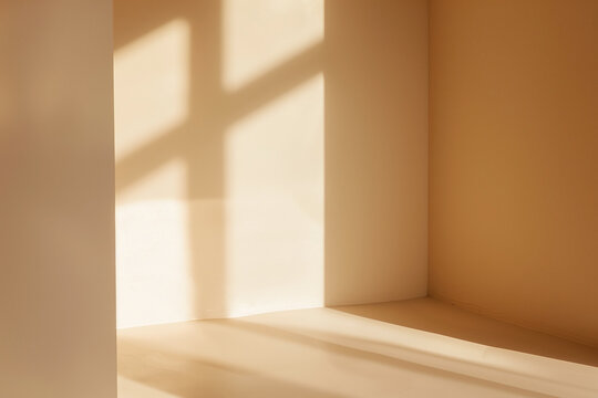 Sunlight streams through a window, casting shadows on the walls of a room with painted in creamy beige tones, creating a warm and inviting ambiance.