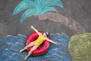 Happy little preschool girl in swimsuit on inflatable ring with sea, sand, palm painted with...