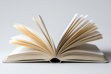 Minimalist white open book with blank pages, laying flat on a seamless white backdrop. 